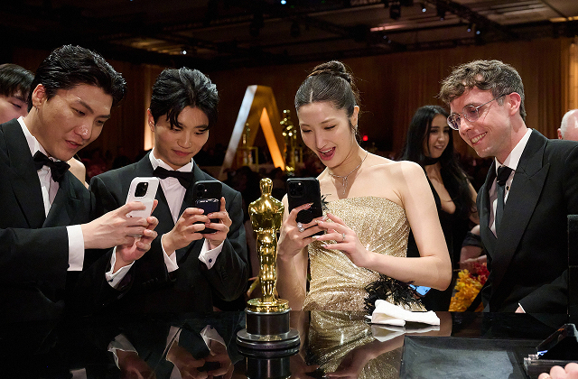 An image of Zhun, Yuhan, and Ejae celebrate together at the Governors Ball, holding their Oscar trophy after the 98th Academy Awards in Hollywood.