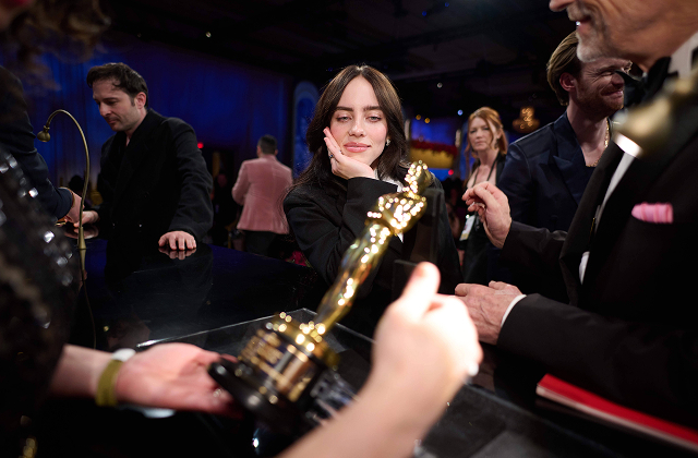 Lizenziertes Bild von Sängerin Billie Eilish, die während der Oscar-Verleihung eine Oscar-Trophäe betrachtet – ein Beispiel für unsere Berichterstattung von Preisverleihungen.