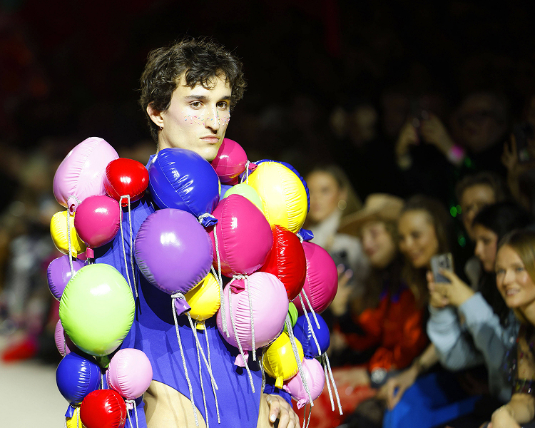 A male model showcases creative design on the runway during Berlin Fashion Week.