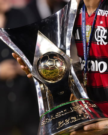 A player holds a golden football trophy.