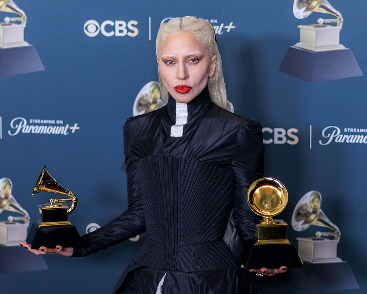 Lady Gaga posiert mit ihren gewonnenen Trophäen bei den Grammy Awards, repräsentativ für lizenzierte Musikbilder.