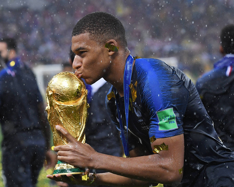 High-resolution contemporary photo of a modern men's football World Cup match, featuring Mbappe holding the World Cup trophy.
